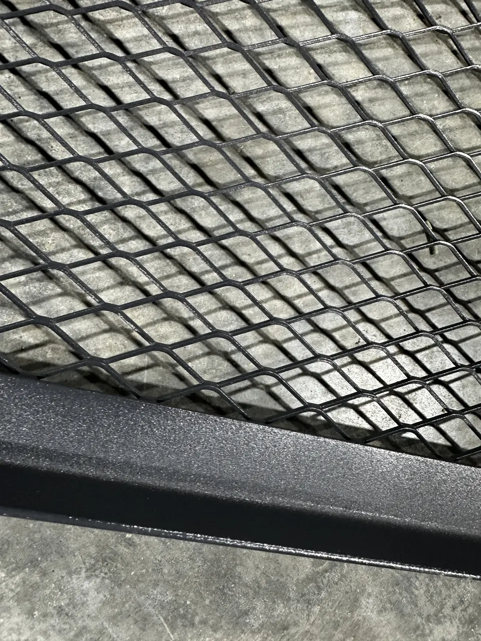 Close-up of the powder-coated expanded metal and textured frame on a window well cover